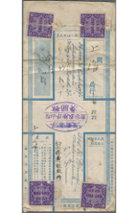 Hochformatiger Standardbriefumschlag, hellblauer Druck,  zum Bargeldversand mit vier blau-violetten Siegelmarken in den Ecken Siegelmarken. Mittig statt Frankatur ein japanischer „Frei für Kriegsgefangene“-Stempel. In den Zwischenräumen Angaben zu Betrag, Empfänger und Absender sowie Kontrollvermerke.